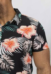 Chemise à manches courtes à boutons noire avec de grandes fleurs d'hibiscus roses et des feuilles de palmier vertes ; tissu léger ; coupe décontractée.