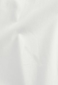 Hvid bomuldsstof med en glat tekstur, der viser subtile folder og plisseringer og blødt reflekterer lyset over overfladen.