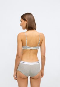 Sutiã cinza de algodão com alças finas e fecho em gancho, combinado com roupa interior hipster cinza com uma faixa branca na cintura e detalhe de logotipo.