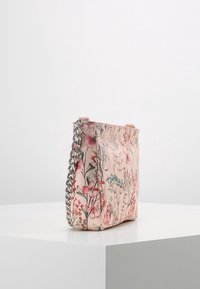 Torba w kwiatowy wzór w delikatnym różowym kolorze, z teksturowaną powierzchnią i srebrnym łańcuszkiem, o prostokątnym kształcie i otwartej konstrukcji.