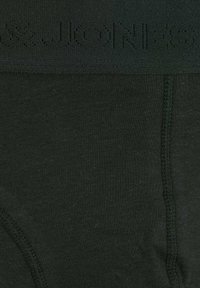 Dunkelgrüne Baumwollslips mit nahtlosem Design, ausgestattet mit einem strukturierten Bund, auf dem "JooN" steht. Glattes Material mit minimalen Nähten.