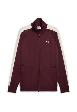 Veste zippée bordeaux en tissu lisse, avec des rayures latérales de couleur crème et un logo blanc sur la poitrine gauche. Comprend des poches zippées.