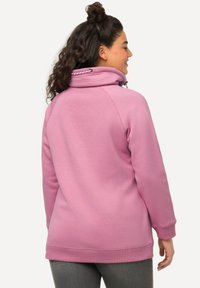 Felpa al collo alto rosa in polare, con coulisse e una vestibilità comoda. Presenta maniche raglan e polsini a costine per un comfort aggiuntivo.