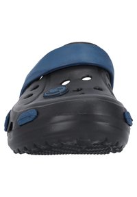 Sabots noirs avec une sangle bleue, présentant plusieurs trous de ventilation et une semelle texturée. Logo circulaire sur le côté.
