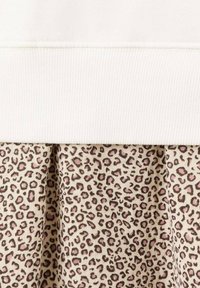 Helles, geripptes Material oben, dazu ein beiges Kleid mit einem Leopardenmuster in Pink und Braun. Weiche Textur durchgehend.