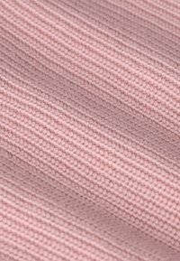 Texturiertes Gewebe in sanftem Rosa mit einem gerippten Muster. Das Material wirkt gestrickt mit einer glatten Oberfläche und zeigt einen leichten Glanz.