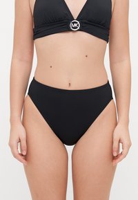 Zwart bikinitop met een driehoekige vorm en een ronde zilveren accent, gecombineerd met hoge taille-broekjes. Gladde textuur en minimalistisch ontwerp.
