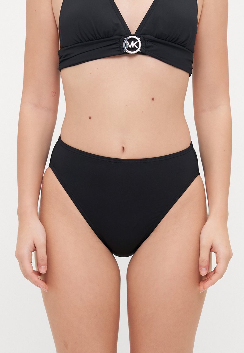Zwart bikinitop met een driehoekige vorm en een ronde zilveren accent, gecombineerd met hoge taille-broekjes. Gladde textuur en minimalistisch ontwerp.