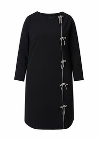 Vestido negro con mangas tres cuartos, que presenta lazos plateados decorativos a lo largo del costado. Tejido suave y corte relajado.