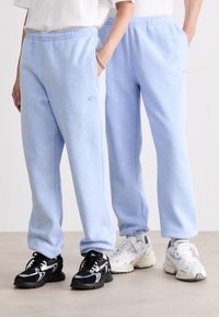 Pantalones de chándal azul claros con cinturilla elástica y bolsillos laterales. Tejido suave con una textura sutil. Presenta un pequeño logo bordado.