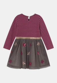 Långärmad klänning med en vinröd randig överdel, guldig midja och grå tyllkjol prydd med paljetterade stjärnmönster i burgundy och beige.