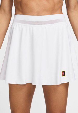 Jupe de sport blanche avec une large ceinture élastique comportant un insert en mesh, de forme évasée, et un petit logo Nike multicolore en bas à gauche.