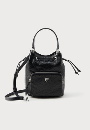 Bolso de cuero negro en forma de cubo con textura acolchada, cierre de cordón y un bolsillo delantero con cremallera que presenta un acento de logotipo plateado.