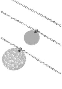Stříbrný náhrdelník se dvěma kulatými přívěsky: jeden je leštěný a hladký, druhý má texturu s kovaným povrchem. Řetízky jsou propojené.