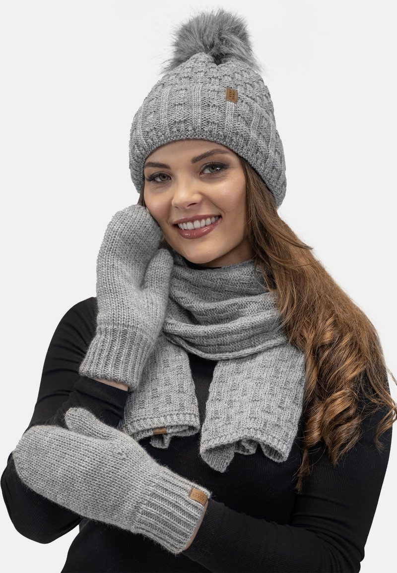 Bonnet en tricot gris avec un pompon, écharpe assortie et gants. Présente des motifs texturés et des poignets côtelés, fabriqué en matériau doux et chaud.