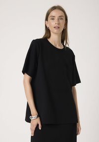 Sort oversized t-shirt lavet af blød bomuld, med korte ærmer, rund halsudskæring og et simpelt, udekoreret design.