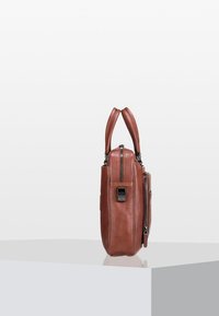 Bolso de cuero marrón con dos asas superiores, un bolsillo lateral con cremallera y una textura suave. Forma rectangular compacta con un diseño minimalista.