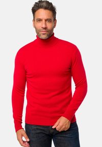Roter Rollkragenpullover aus geripptem Strick mit langen Ärmeln und enger Passform, kombiniert mit dunkelblauen Jeans.