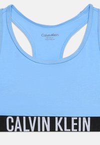Αθλητικό σουτιέν Calvin Klein σε ανοιχτό γαλάζιο χρώμα με σχέδιο racerback και μαύρη ελαστική ταινία με λευκή σήμανση Calvin Klein.