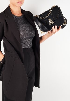 Zwarte leren handtas met gouden hardware, kettingriem en studdetail. Iets gestructureerde vorm met decoratieve accenten.