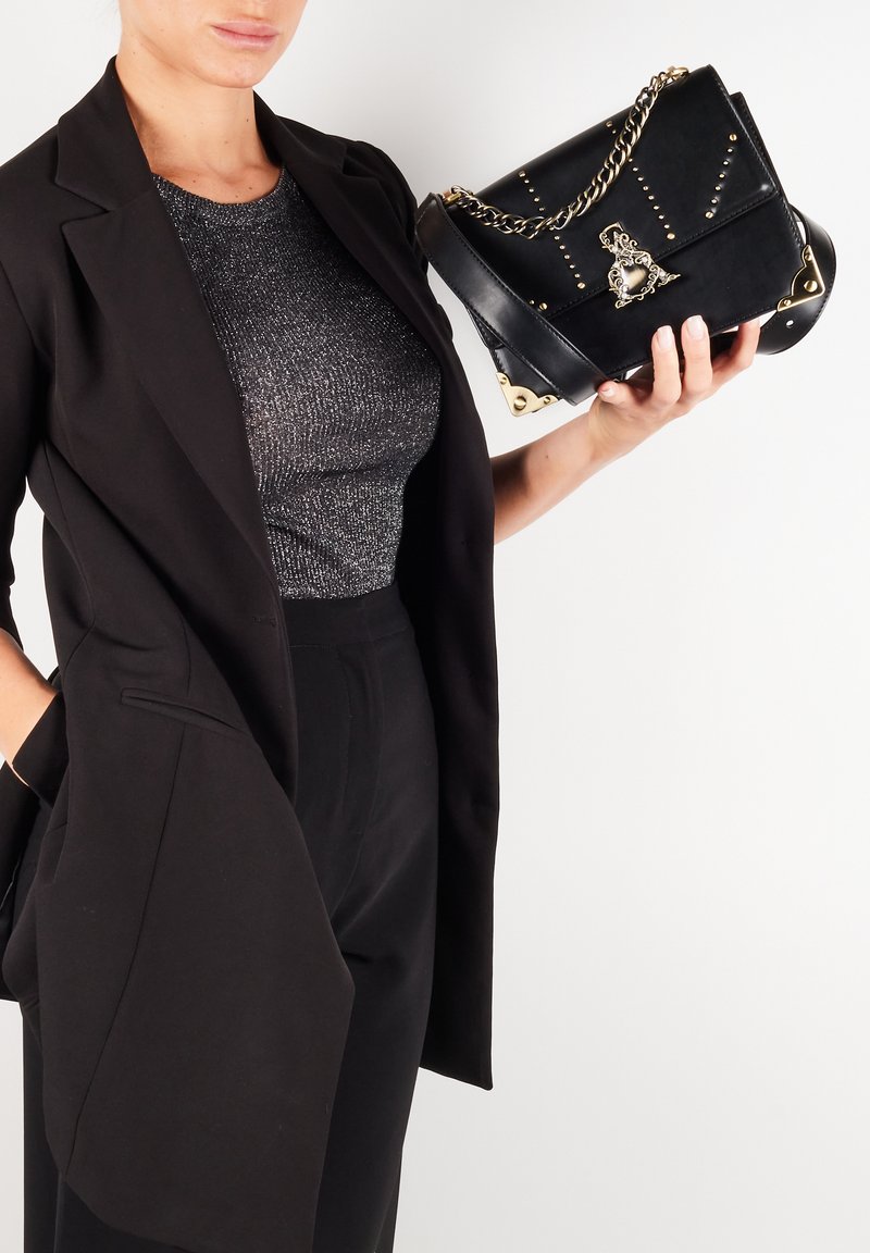 Czarna skórzana torebka z złotymi akcentami, łańcuszkowym paskiem i ćwiekowanymi detalami. Lekko usztywniony kształt z ozdobnymi akcentami.
