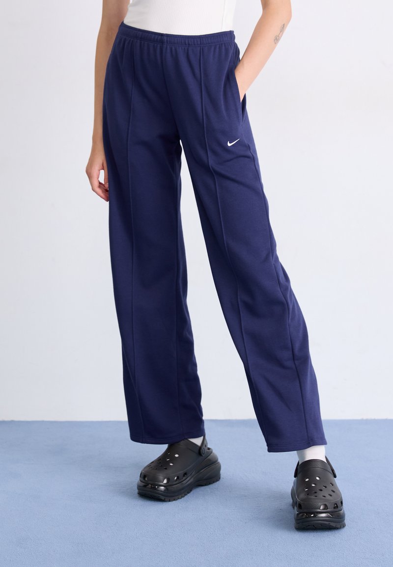 Marineblauwe sweatpants met een elastische tailleband, zijzakken en een klein wit Nike-logo. Gecombineerd met zwarte plateauklompen.