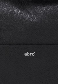 Czarna skórzana torba o teksturowanej powierzchni. Posiada srebrne logo "abro" oraz elegancki, minimalistyczny design. Gładki, zorganizowany kształt.