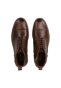 Bottines en cuir marron avec fermeture à lacets et zipper, bout rond, couture contrastante et accents texturés sur les côtés.