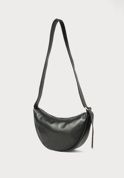 Schwarze Schultertasche aus Kunstleder mit runder Form, verstellbarem Tragegurt und Reißverschluss. Glatte Textur mit minimalistischem Design.