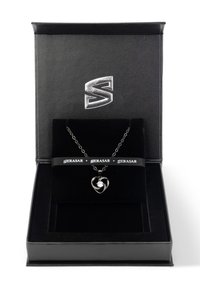 Silberne herzförmige Halskette mit spiralförmigem Detail, platziert in einer mit schwarzem Samt ausgekleideten Schmuckschatulle mit einem silbernen Logo auf dem Deckel.