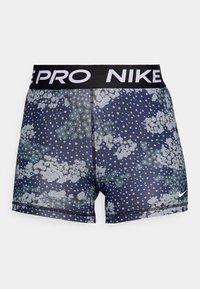 Granatowe spodenki sportowe z kwiatowym wzorem w jasnoszarym i zielonym kolorze, z czarnym elastycznym pasem w talii z napisem "NIKE PRO".