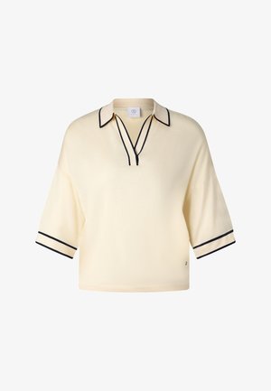 Kremowy sweter na krótki rękaw z czarną lamówką na kołnierzu, dekolcie i mankietach, o luźnym kroju i otwartym, V-kształtnym dekolcie.