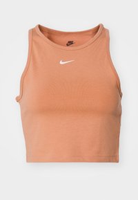 Bezrękawnik w kolorze terakoty, z białym logo Nike Swoosh na środku klatki piersiowej oraz czarnym logo Nike wewnątrz kołnierza.