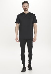 Svart tränings t-shirt i lätt material, kombinerad med figurnära svarta leggings med sidodetaljer och logotyp.