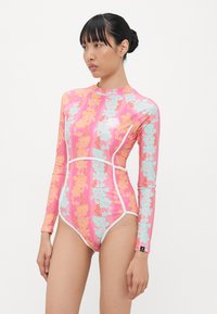 Maillot de bain à manches longues rose avec un motif floral en orange et bleu clair, avec des accents blancs et un design ajusté.