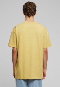Lys gul, kortærmet t-shirt med afslappet pasform; glat tekstur og rund udskæring. Ingen synlige logoer eller mønstre.