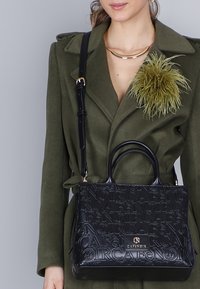 Borsa a tracolla in pelle nera con motivo testurizzato a rilievo, manici tondi e tracolla rimovibile. Presenta un accento del logo dorato sulla parte anteriore.