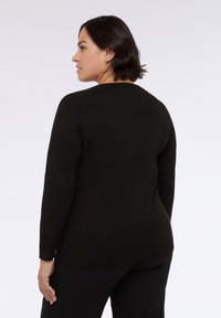 Maglione nero a maglia con scollo rotondo, maniche lunghe e fondo a coste. La texture appare morbida e leggermente aderente in vita.