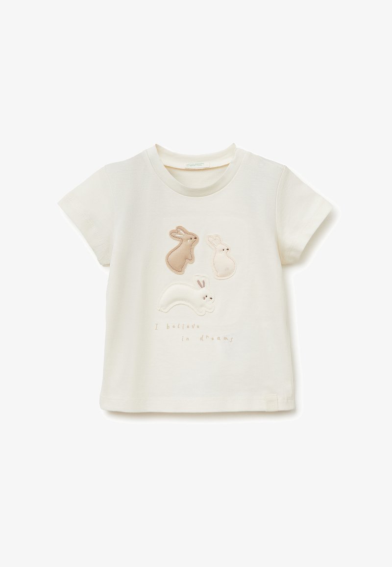 T-shirt pour tout-petit de couleur crème avec trois appliques de lapins cousues et la phrase "Je crois aux rêves" en texte brun clair.