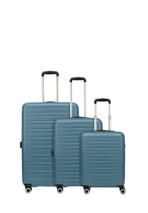 Tre valigie rigide con una finitura blu opaca, caratterizzate da strisce testurizzate, manici telescopici e quattro ruote per la mobilità.