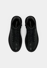 Une paire de baskets montantes noires en cuir avec des lacets et des détails de zip, vues du dessus sur un fond blanc.