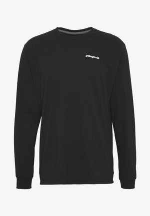 Schwarzes Langarm-T-Shirt aus Baumwolle, mit Rundhalsausschnitt und kleinem weißen "Patagonia"-Logo auf der Brust. Glatte Textur.