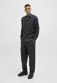Camisa de lino gris oscuro de manga larga con botonera, combinada con pantalones holgados a juego y zapatos oscuros. Diseño sencillo y casual.