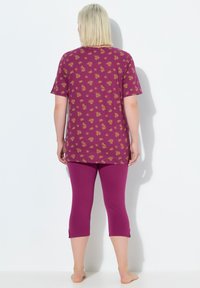 Camiseta de manga corta con estampado floral en púrpura, combinada con leggins capri en púrpura sólido. Tejido suave y elástico, con un corte relajado.