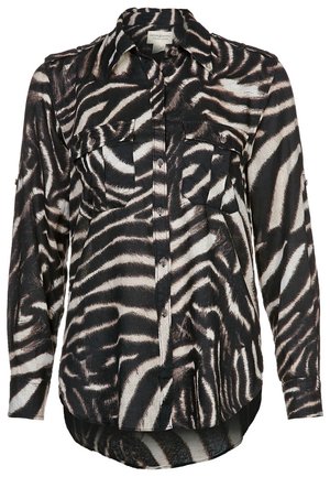 Musta-valkoinen seepra-kuvioinen pitkähihainen napillinen paita, jossa kaksi rintataskua ja kaulus, hieman pidempi takahelma.