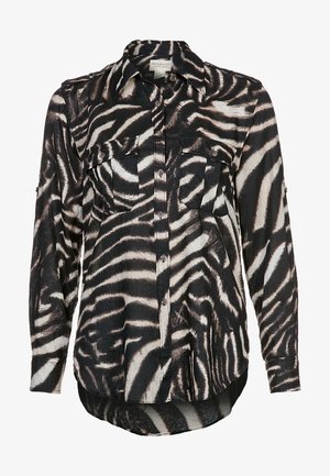 Chemise à manches longues à boutons avec imprimé zèbre noir et blanc, dotée de deux poches poitrine et d'un col, ourlet arrière légèrement plus long.