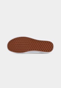 Semelle de chaussure en caoutchouc avec un motif gaufré en brun, bord blanc, fond plat, isolée sur un fond gris clair.