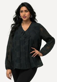Blusa nera, testurizzata, con scollatura a V, caratterizzata da maniche lunghe trasparenti e un motivo a strati. Progettata con polsini elastici e una vestibilità ampia.