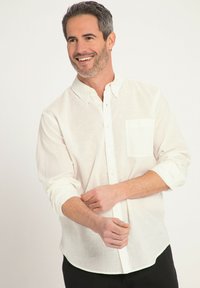 Weißes Leinenhemd mit Button-Down-Kragen, einer Brusttasche, langen Ärmeln, die an den Manschetten hochgekrempelt sind, und abgerundetem Saum.