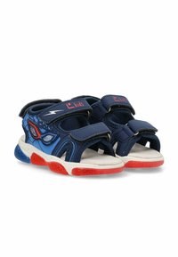 Sandalias infantiles azul marino con correas de Velcro, acentos azul claro, suela roja y una plantilla texturizada blanca, con un diseño divertido.